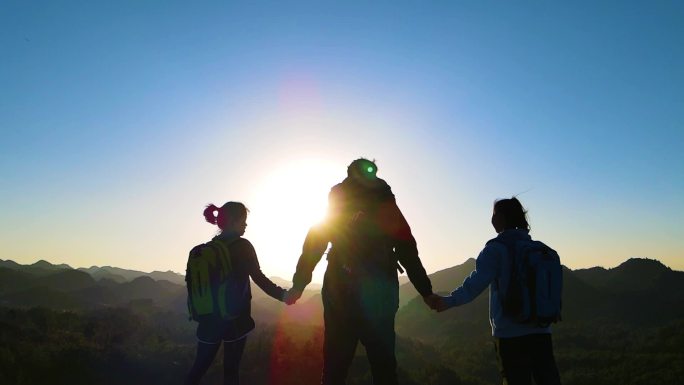 团队山顶手拉手欢呼庆祝成功登顶攀登顶峰