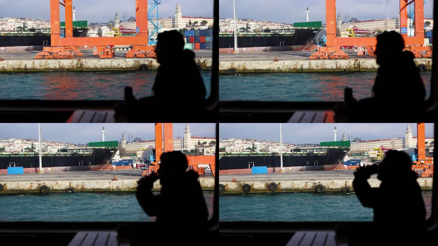 在船上旅行的人的剪影，站在移动的轮船上的年轻人思考并环顾四周，从游轮上观看令人惊叹的城市景观和造船厂