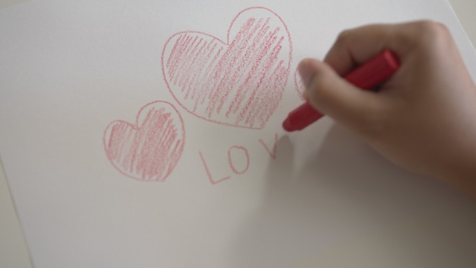 女人的手用蜡笔在白纸上写一个红色心形的爱