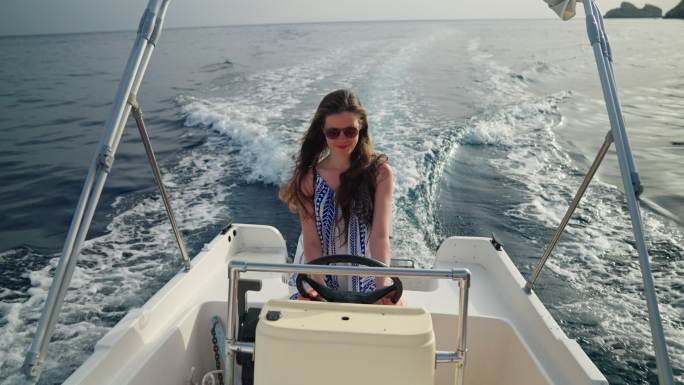 可爱而快乐的女孩驾驶快艇在梦中度假。愉快的微笑