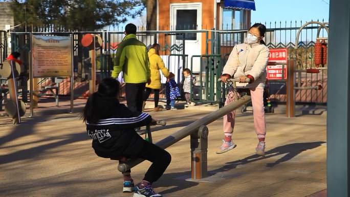冬季公园健身场大人陪小孩玩跷跷板人文纪录
