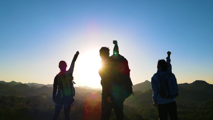 团队登山背影攀登者山顶向着太阳呐喊旅行者