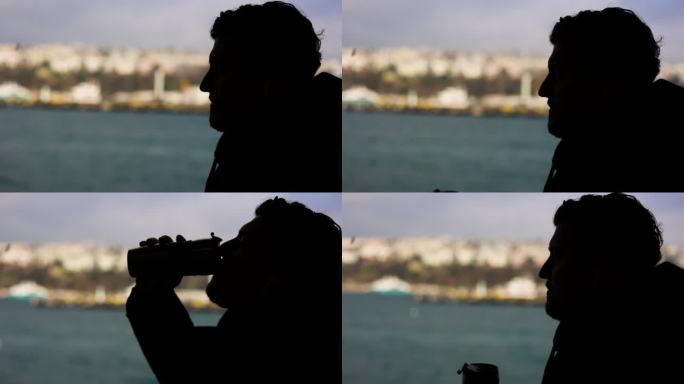 一个男人在船上旅行的剪影，在伊斯坦布尔博斯普鲁斯海峡的景色下喝咖啡，从游轮上观看壮丽的城市景色，在船