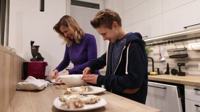 母亲和十几岁的儿子准备饭菜