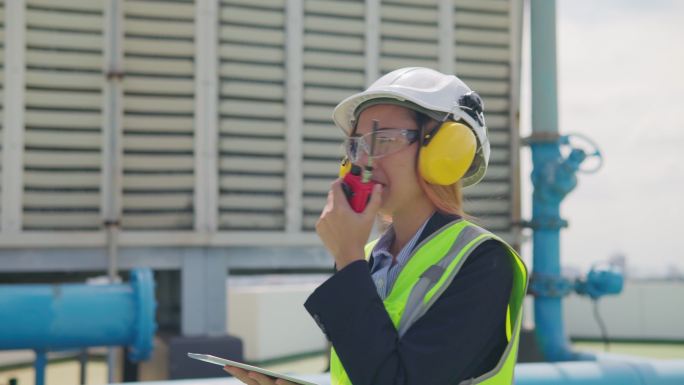 亚洲女性维修工程师检查大楼露台上的工作，大楼空调系统的维护