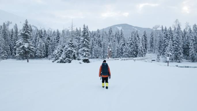 4K冬季冰天雪地中背着包行走的摄影师背影