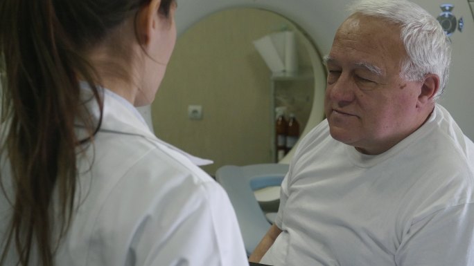 放射科医生正在准备医用扫描仪。与患者交谈，帮助他做好手术准备。