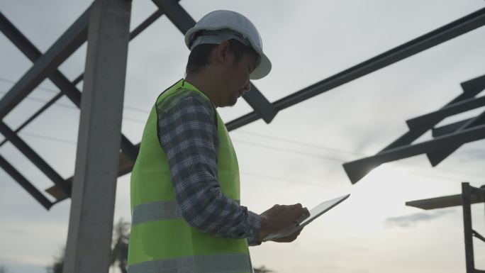 亚洲检查员工程师正在参照建筑标准检查房屋。检查工程师正在使用基于平板电脑的检查技术检查结构。