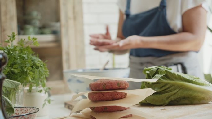 一位女士在厨房里为汉堡肉饼整形牛肉