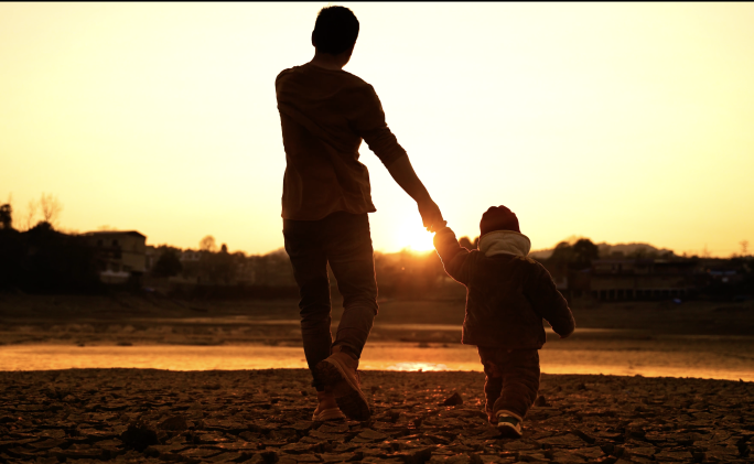 父子夕阳下父亲牵着儿子的手在湖边散步日落