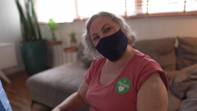 一位戴着“Fui vacinado”（接种疫苗）贴纸的老年妇女的肖像——戴着口罩