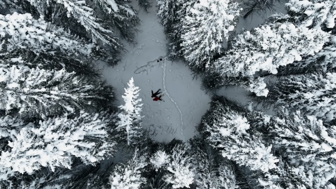 4K躺着森林雪地上的两个人航拍