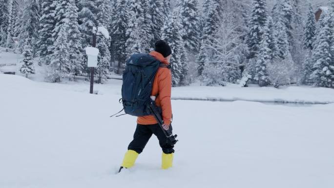4K冬季冰天雪地中背着包行走的摄影师