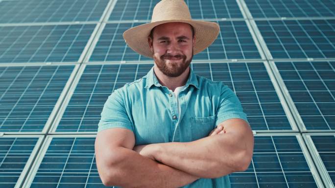 自信的农民站在太阳能电池板前。人们对最新的可再生能源光伏组件安装感到满意。现代技术使农场生活更轻松和