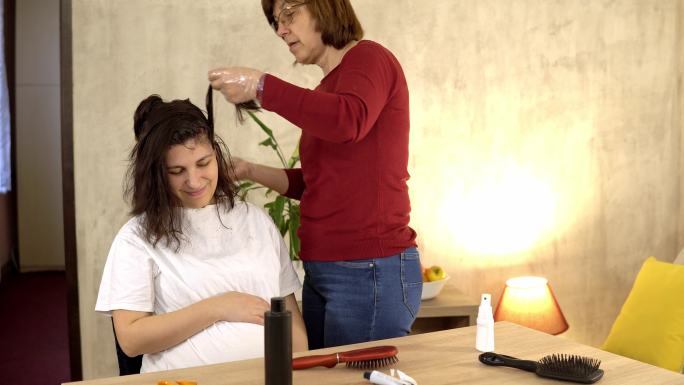 一位年长的妇女给在家怀孕的女儿染发。