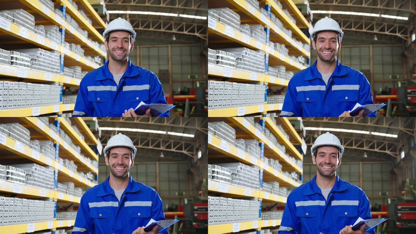 在工厂仓库工作的白人男性工业工人的肖像。迷人的男性工业工程师在制造厂独自处理订单和产品，然后微笑着看
