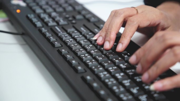 女性用手在键盘上打字。