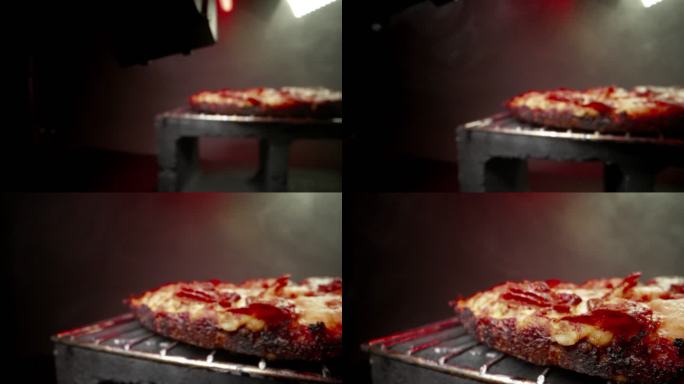 广角推镜头展示美味的蒸热深碟辣椒香肠披萨新鲜出炉，放在带有复印空间的加热灯下的冷却架上