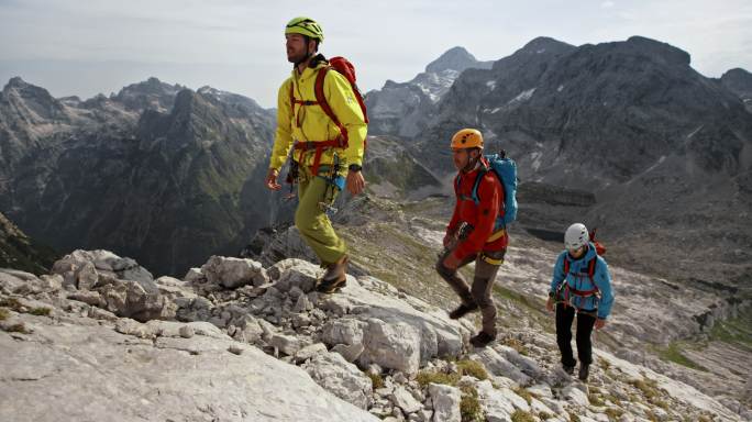 三名登山者在阳光下走上岩石山坡