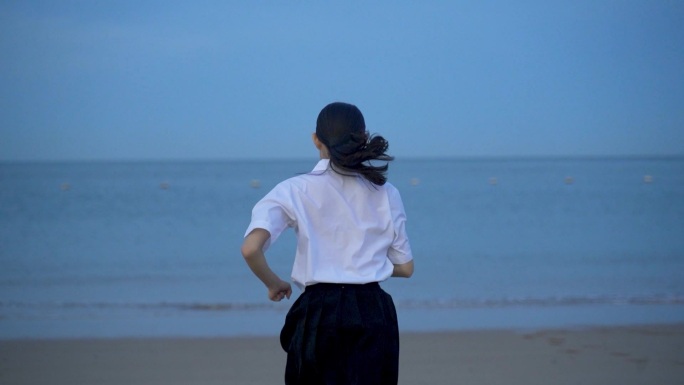 女孩跑向大海回头看海边欢快奔跑的美女青年