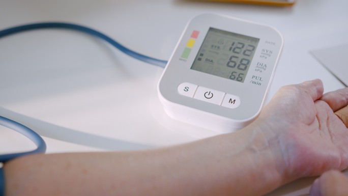 老年妇女在家中用医疗器械检查血压计和心率。