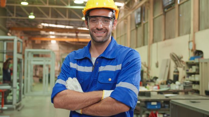 在工厂仓库工作的白人男性工业工人的肖像。迷人的男性工业工程师在制造厂独自处理订单和产品，然后微笑着看