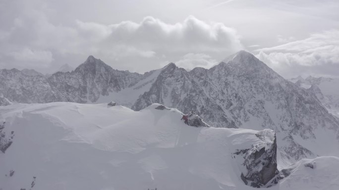 在奥地利阿尔卑斯山区，一位登山者走在冰雪覆盖的山脊上，雪迎面而来