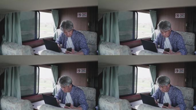 度假期间，亚洲中国老年男子早上在露营车上用笔记本电脑打字