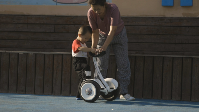 小区社区老人带小孩调皮骑平衡车