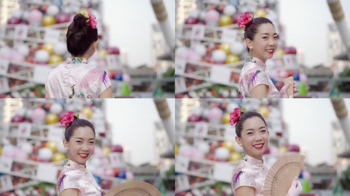 一位身着平底宝西装的中国女子在城市里微笑着拿着扇子。