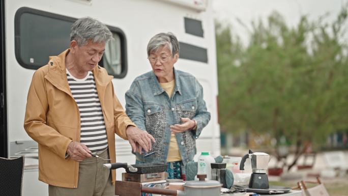 在周末休闲活动期间，亚裔中国老年夫妇在露营车旁准备早餐