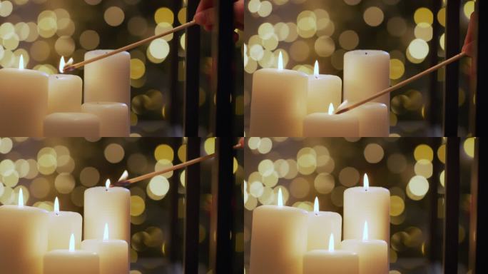 一只手点亮美丽的圣诞蜡烛，背景是圣诞灯，只有蜡烛在相机的焦点