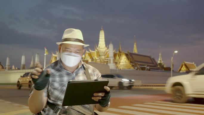 轮椅旅游地标曼谷概念。坐在轮椅上的游客使用手机拍摄大皇宫（Wat Phra Kaew）的照片，并使用