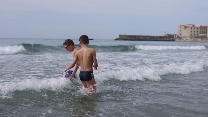 在西西里小镇的海滩上玩球的青少年