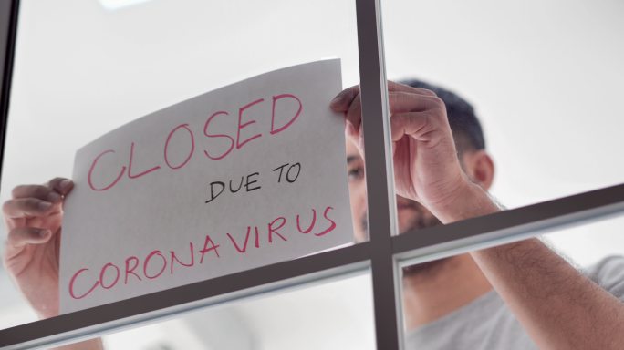 由于冠状病毒肺炎疫情，一名混血儿企业主在前门挂上了“关闭”标志。信息标志、小型企业、封锁、意外、战胜