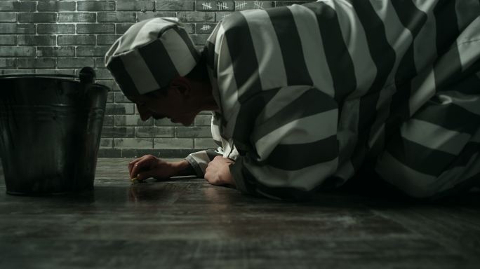 罪犯在惩教所用牙刷清洁牢房地板