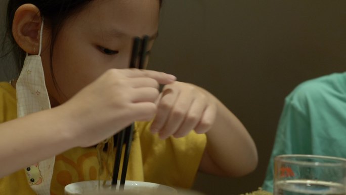 快乐的亚洲女孩与家人一起在餐厅吃面条、寿司、火锅或火锅，生活方式理念。