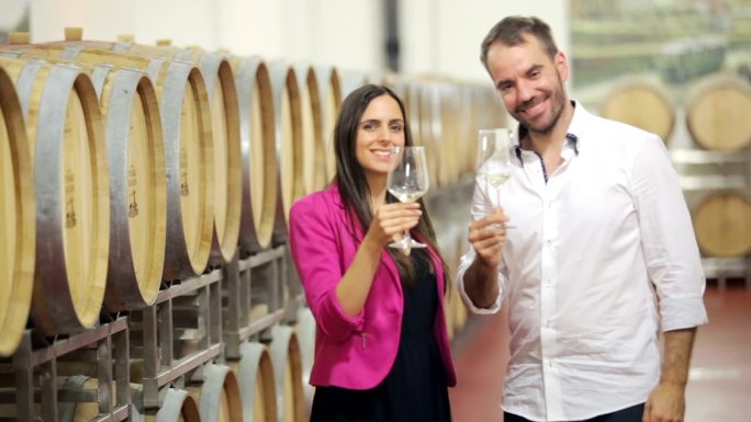 幸福的夫妇在葡萄酒窖里喝白葡萄酒