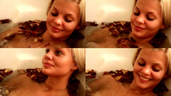 美丽的女人在热浴盆里有花瓣