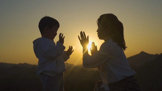 亲子击掌游戏妈妈陪伴小孩母子逆光剪影母爱