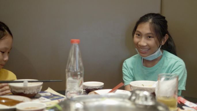快乐的3个亚洲女孩与家人一起在餐厅吃寿司、火锅或火锅，生活方式理念。
