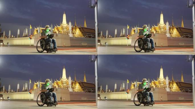 轮椅旅游地标曼谷概念。坐在轮椅上的游客使用手机拍摄大皇宫（Wat Phra Kaew）的照片，并使用
