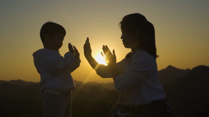 母子击掌游戏亲子逆光剪影温馨家庭年轻妈妈