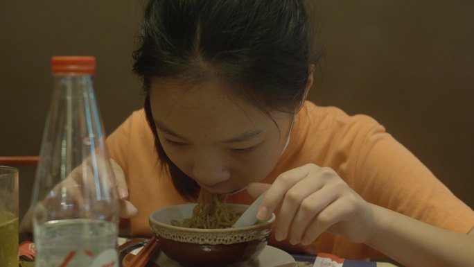快乐的亚洲女孩与家人一起在餐厅吃面条、寿司、火锅或火锅，生活方式理念。