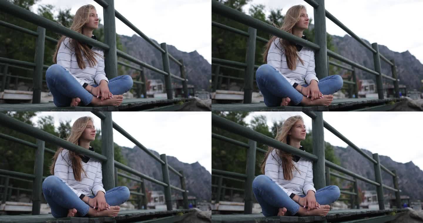 十几岁的女孩坐在Limone sul Garda的一座桥上，欣赏Garda湖的景色