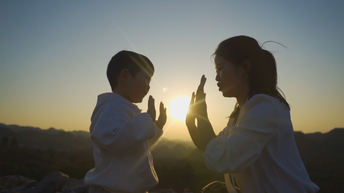 妈妈陪伴小孩玩拍手游戏击掌逆光剪影儿童节