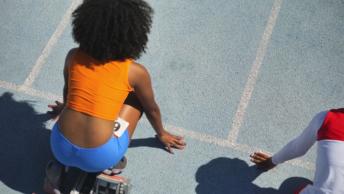 女子田径运动员在阳光充足的跑道上起跑