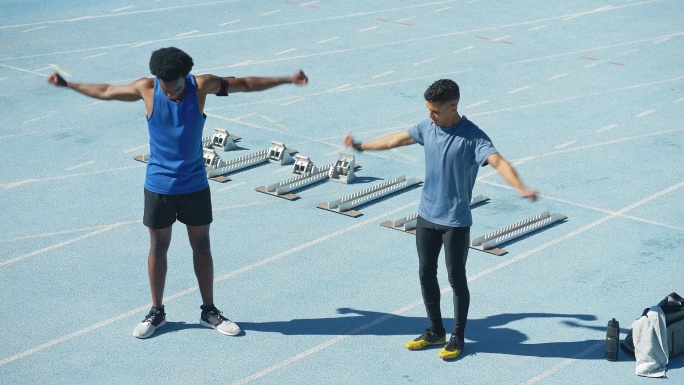 年轻男子田径运动员在阳光充足的跑道上热身