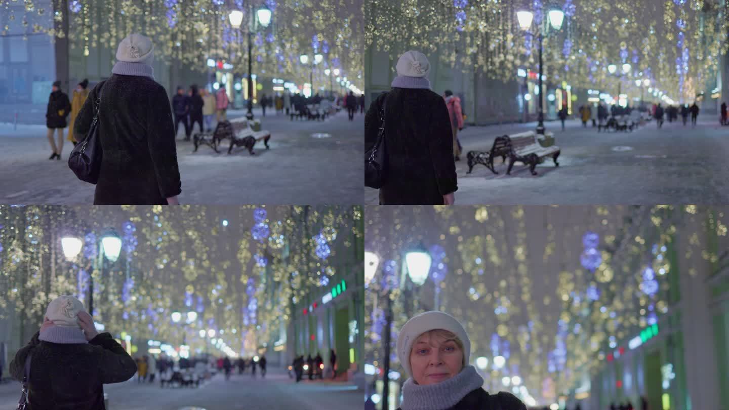 在圣诞节和新年期间，一位迷人的成熟女性，一位游客，正沿着灯火通明的街道走着，在一个大城市享受节日装饰