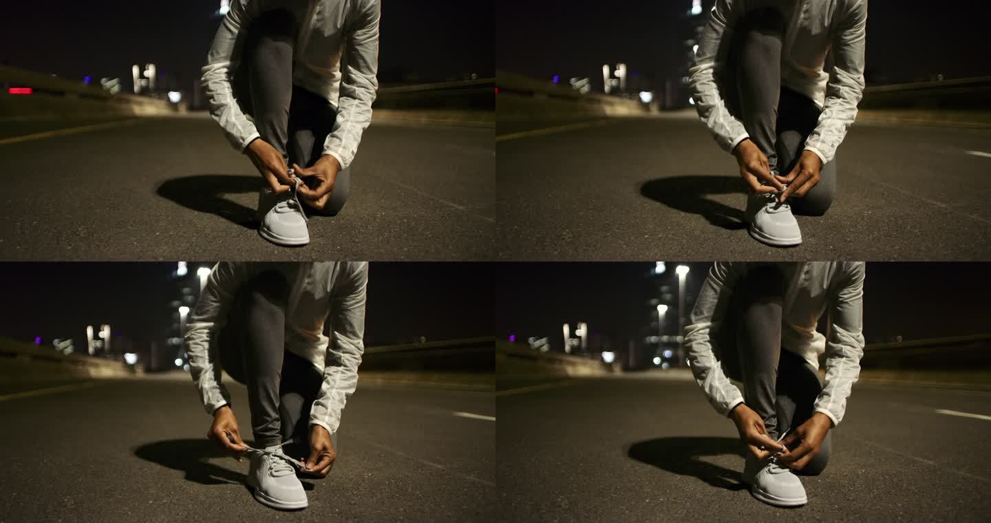 4k视频画面显示，一名无法辨认的女子在夜间在城市道路上跑步前系鞋带
